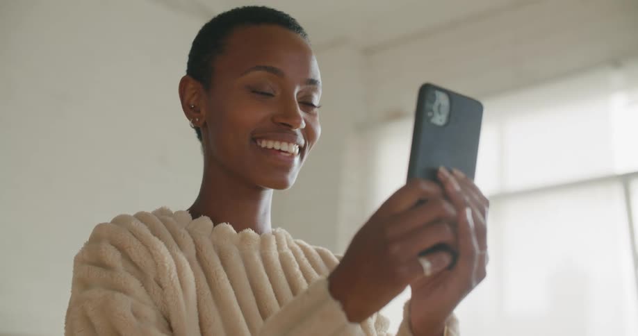 A woman smiles and waves at her phone during a video call