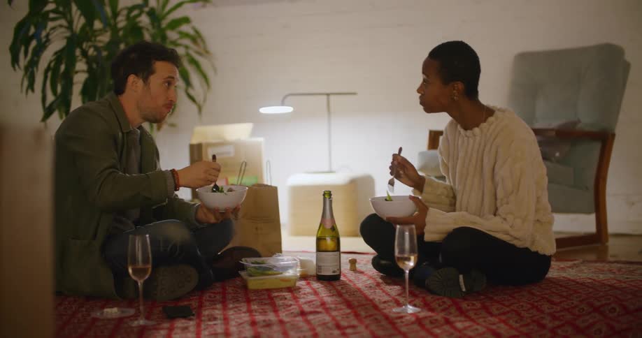 Couple sits on living room rug eating