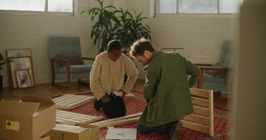 A man and a woman on the floor on a carpet with chairs and walls in the background