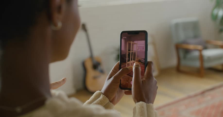 A woman uses augmented reality on a smartphone to plan the placement of furniture in her living room