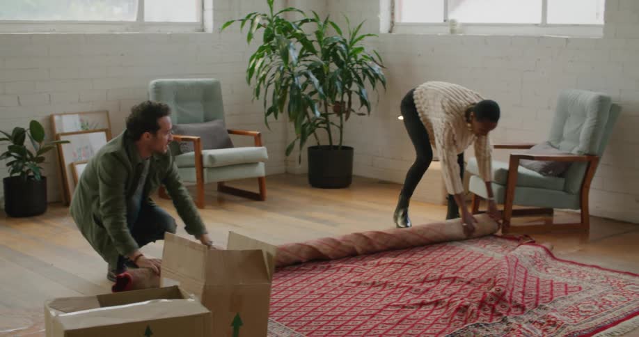 A man and woman unrolling a rug