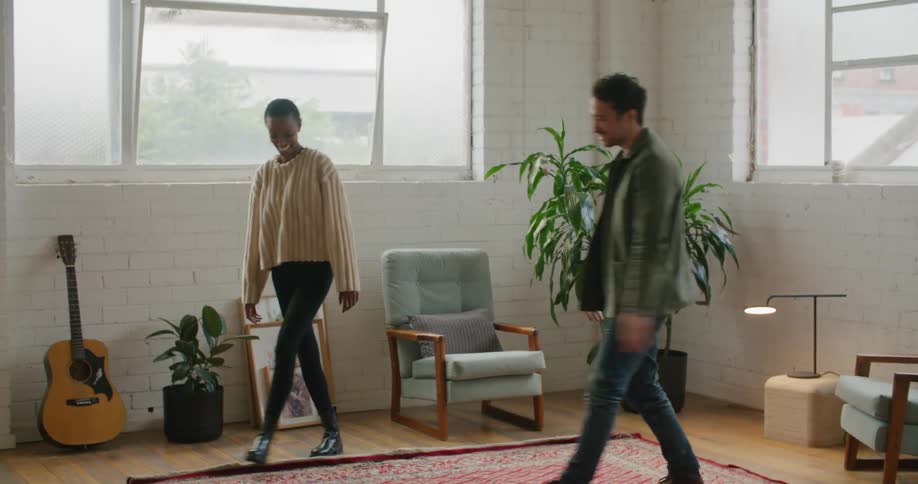 A man and a woman in a room giving each other a high five with walls and windows in the background