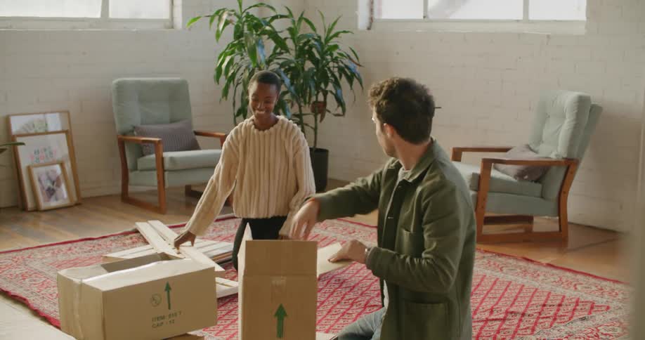 A man and a woman on the floor on a carpet with chairs and walls in the background