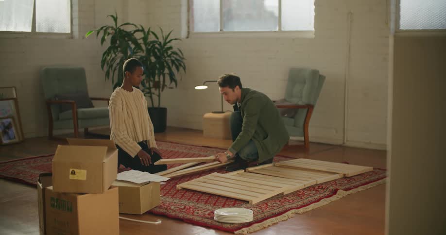 A man and woman lay out the wooden pieces of a piece of furniture before putting it together