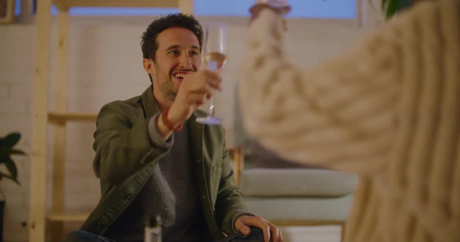 A woman pours champagne and laughs as she toasts and drinks with a man