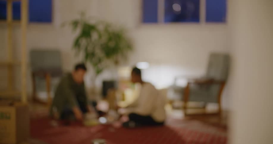 Young couple eating dinner on the floor in the living room at home