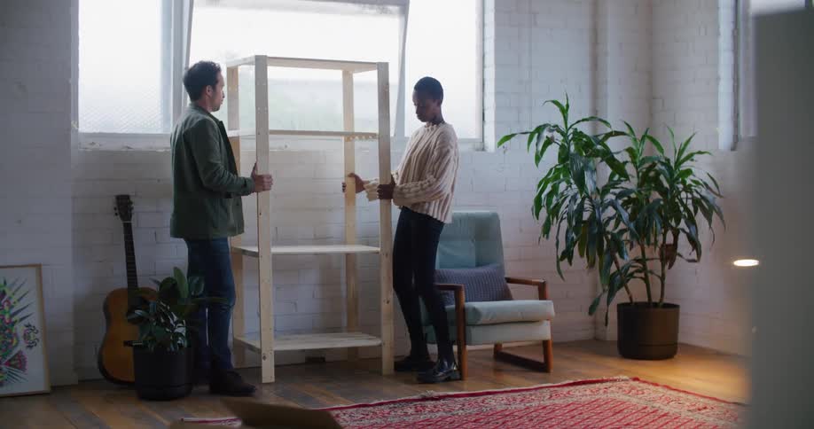 A man and woman moving a shelf around