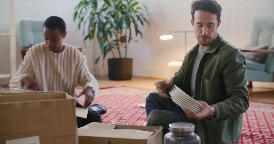 A man and a woman on the floor unpacking boxes with plants and walls in the background