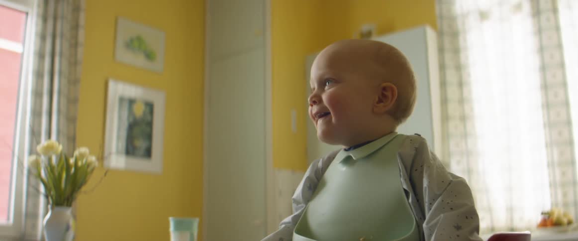 A baby pushes up to try and get out of his highchair in the kitchen