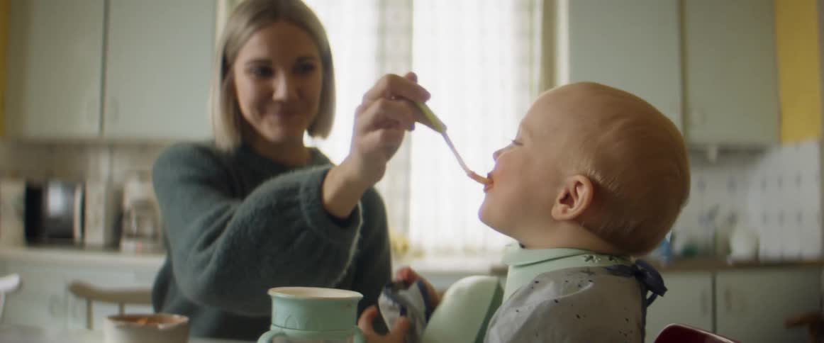 A mother and father feeding a baby