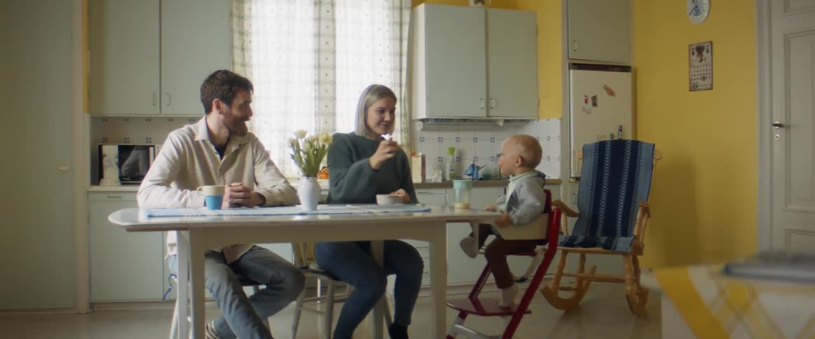 A man a woman and a child sitting at a table in a kitchen