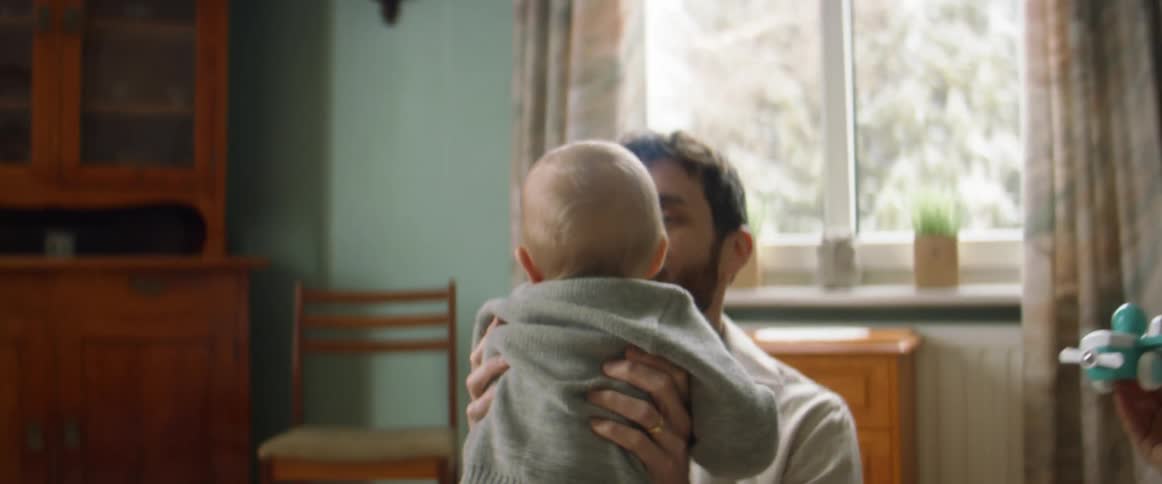 Parents sit on the floor with their infant son playing with a toy plane