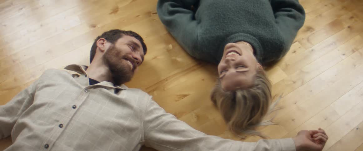 A man and woman lying on the floor talking smiling and touching