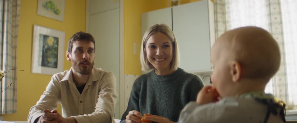 A mother and father feeding a baby oranges