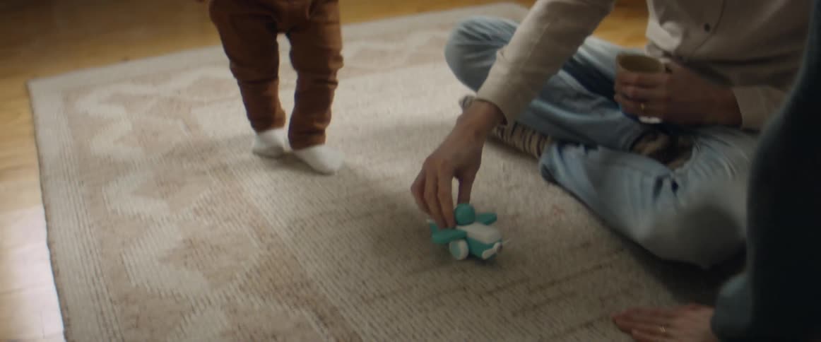 Couple sitting on rug play with toy plane and toddler