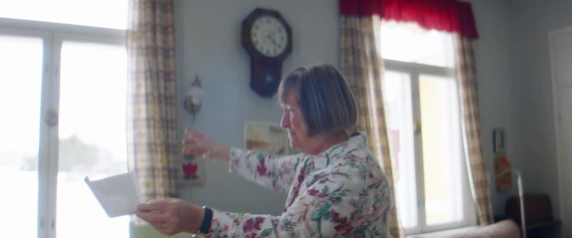 A future mother and father showing a grandmother a picture
