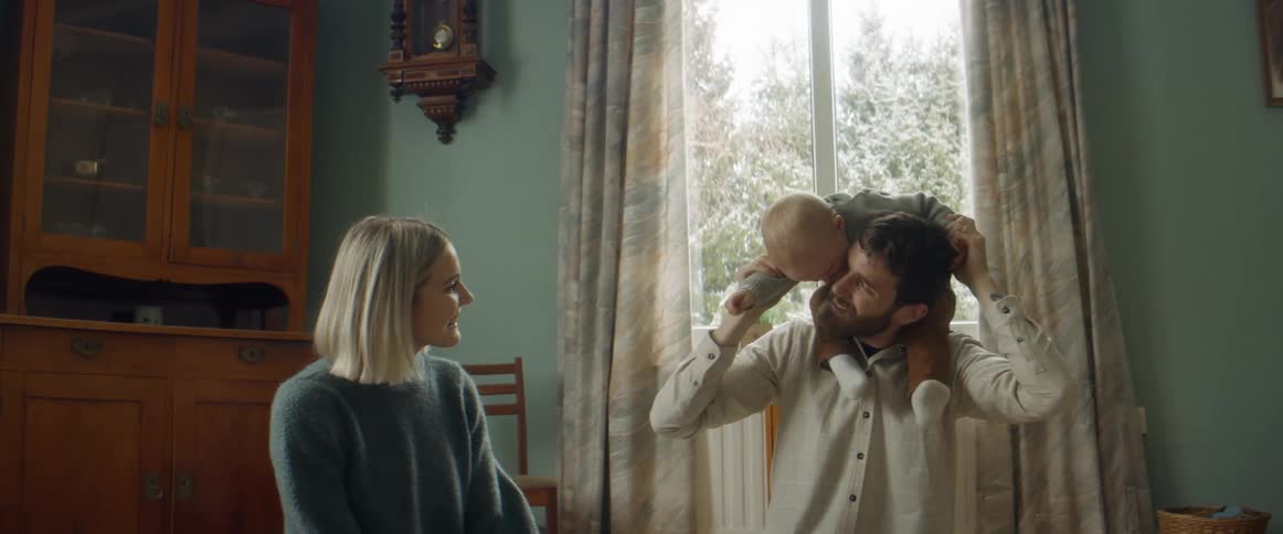 Family play sitting on floor in room near window showing winter covered trees