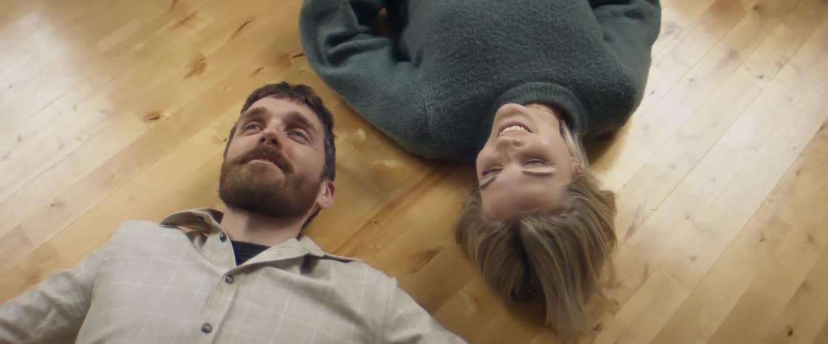 A man and woman laying on the floor smiling and talking