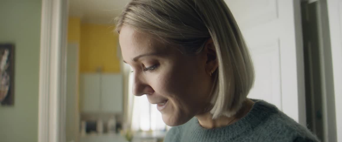 A woman with a sweater in a room with a doorway and window in the background