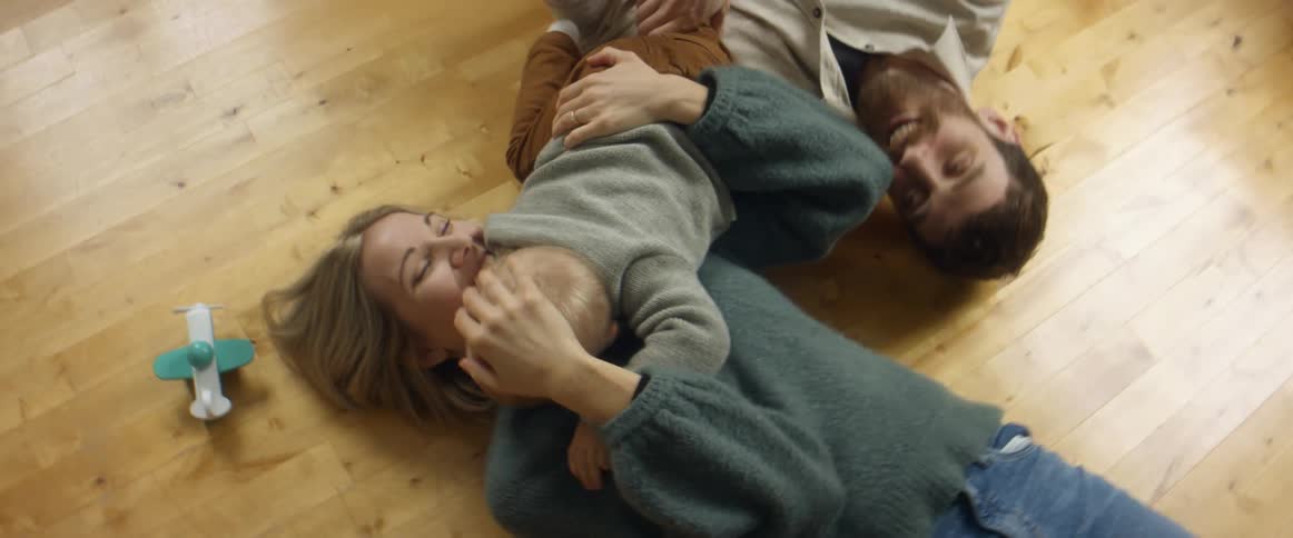 A mother and father playing with their baby on the floor