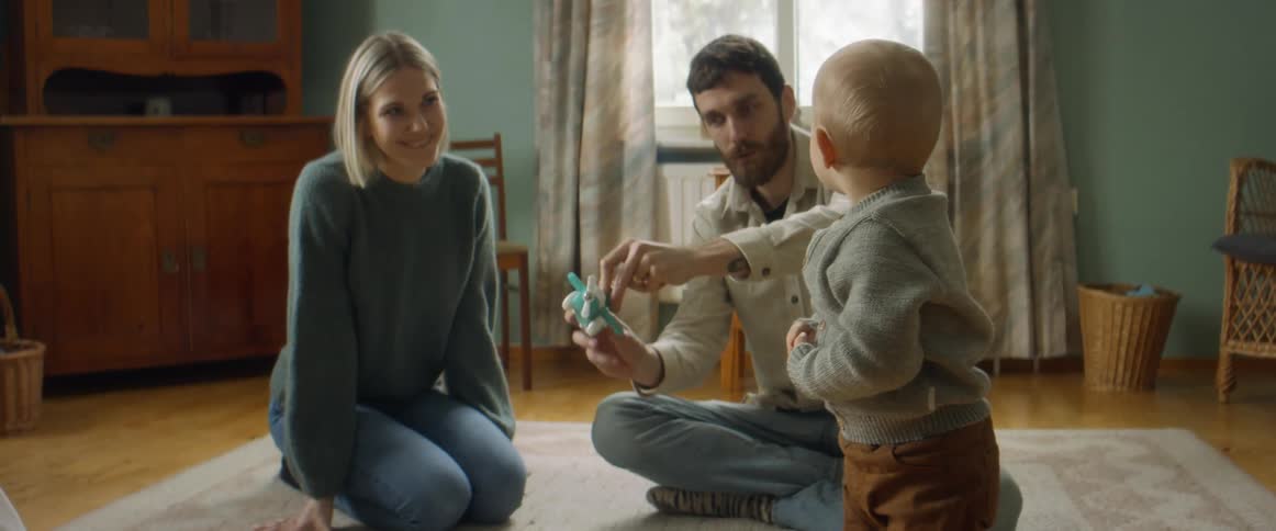 A mother and father playing with a toy with their son
