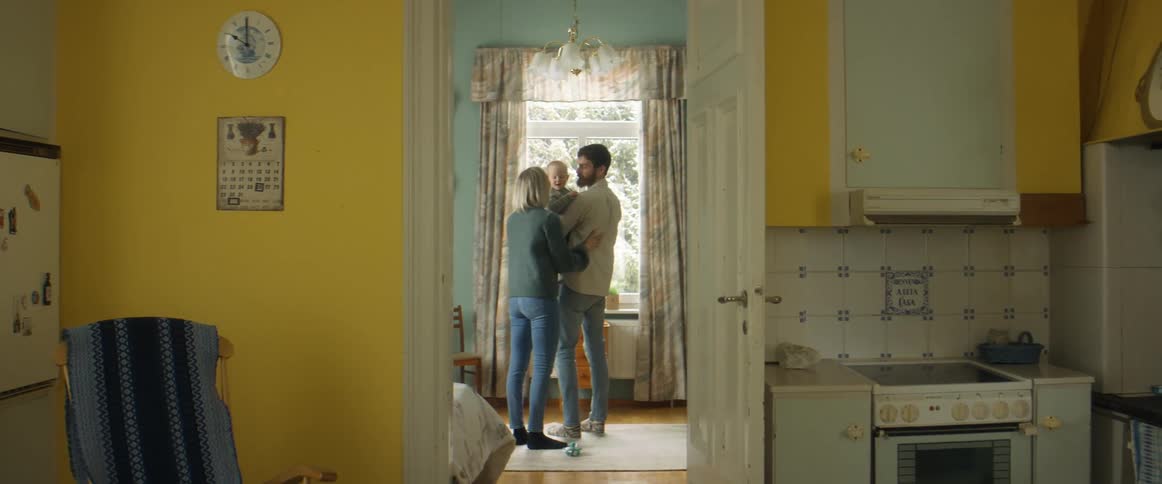 A dad twirls around with his young son in his arms while mom stands close by