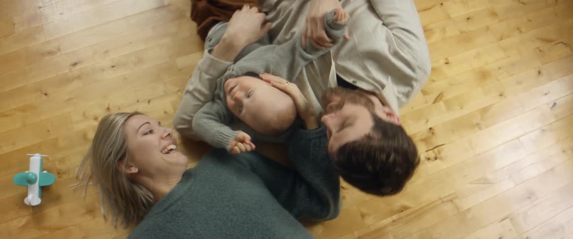 A man a woman and a baby playing on the floor