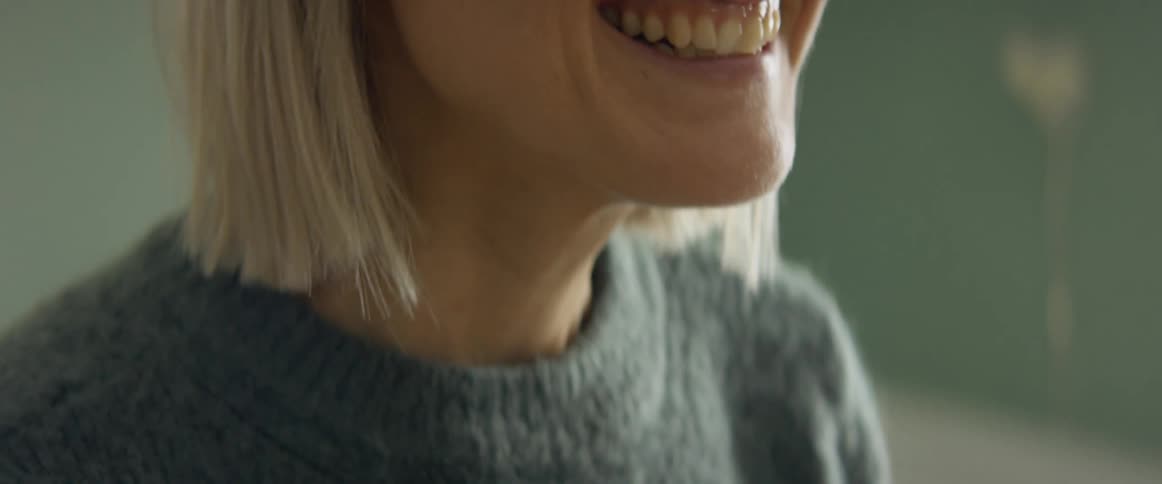 Blonde woman wearing a sweater shares important announcement smiling and hugging someone