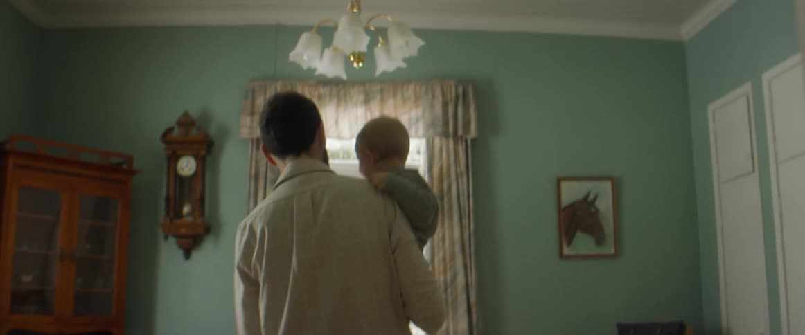 A father carrying his child through the house to his wife