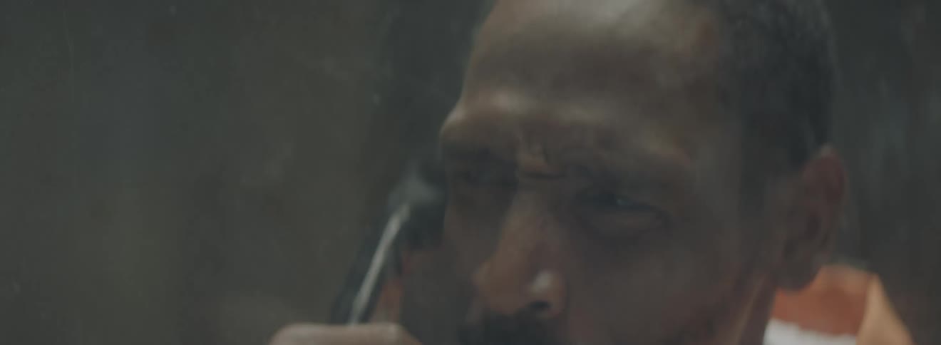 A man in a prison outfit talking on a phone