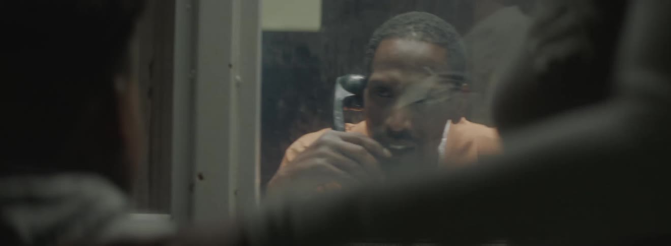A man in prison talking to two other people on a phone