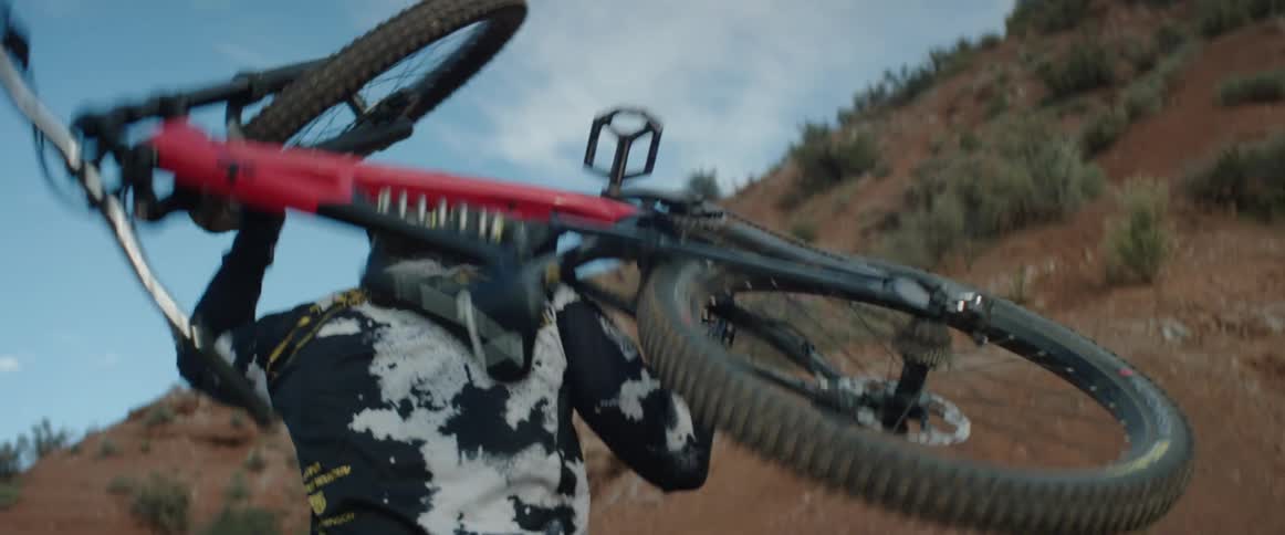 A person carrying a mountain bike up a hill