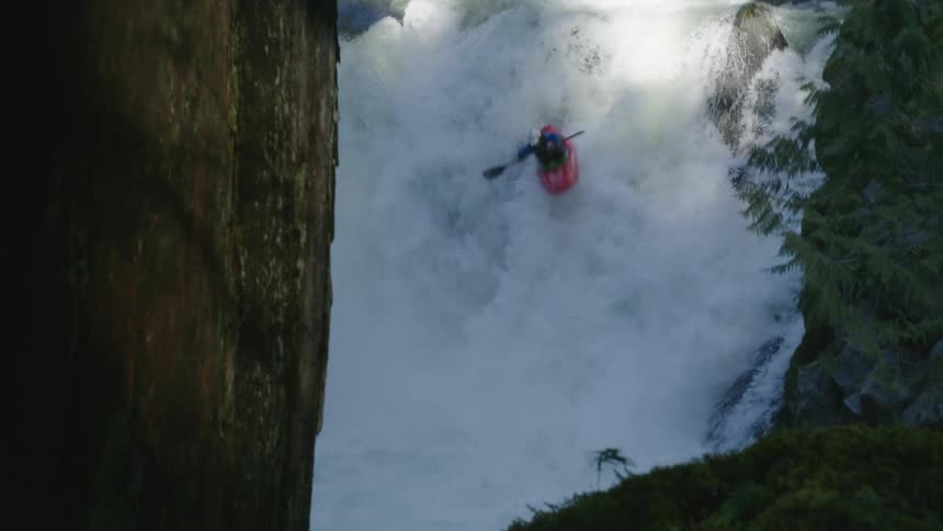 Real time shot of a man paddling over a large waterfall in the pacific northwest in late evening golden light