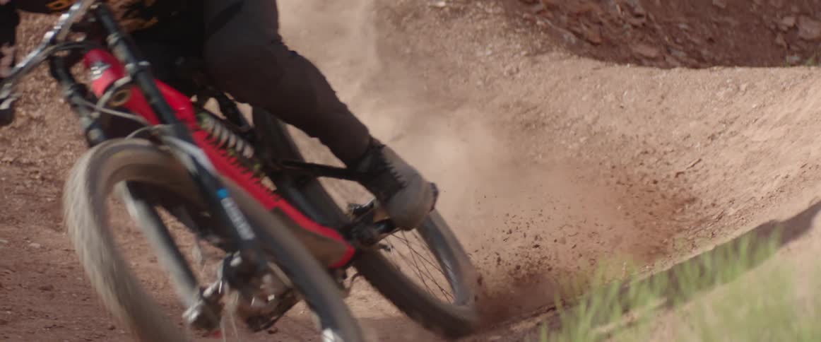 Dirt flies up as a bicyclist rides through a tight dusty corner on a trail