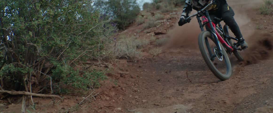 A person carving a mountain bike down a steep dirt chute in the desert