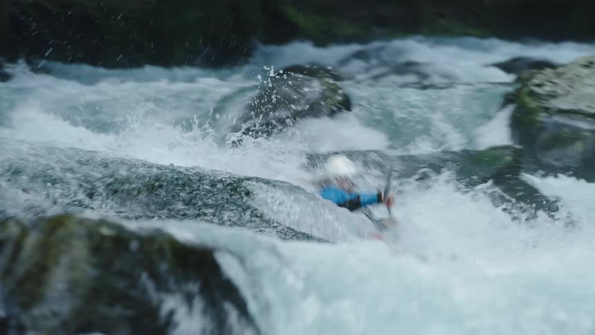 Man enters a steep and dangerous whitewater rapid in a red kayak and white helmet