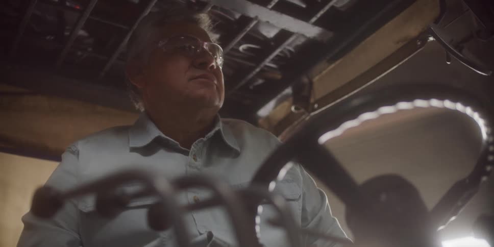 A man with glasses and gloves driving a vehicle with a steering wheel