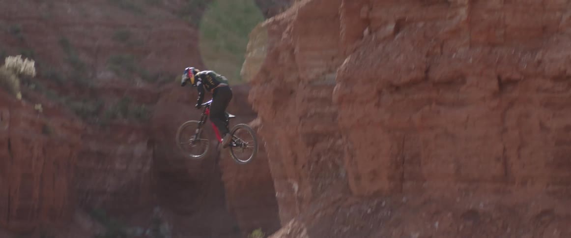 A mountain bike athlete does a 360 off a large desert drop
