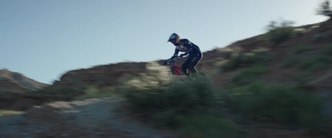 Man riding a mountain bike riding down the slope of a mountain in the desert at morning