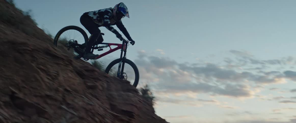 A man riding a mountain bike down a hill after sunset