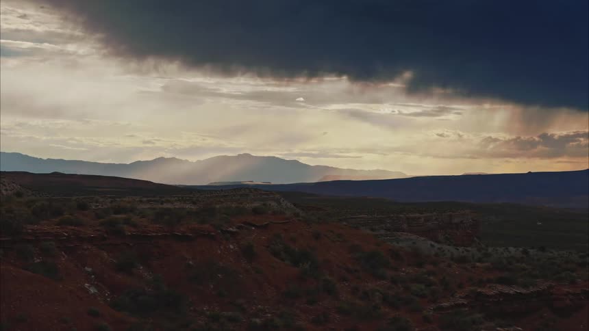 A desert landscape with a distant mountain range and stormy sky and clouds