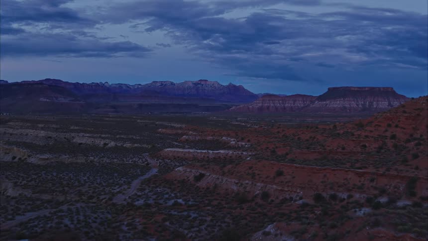 An aerial view of a desert mesa area at dusk with distant mountains