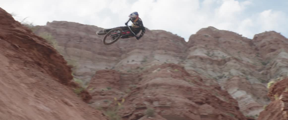 Man riding a mountain bike jumping over the slope of a mountain in the desert