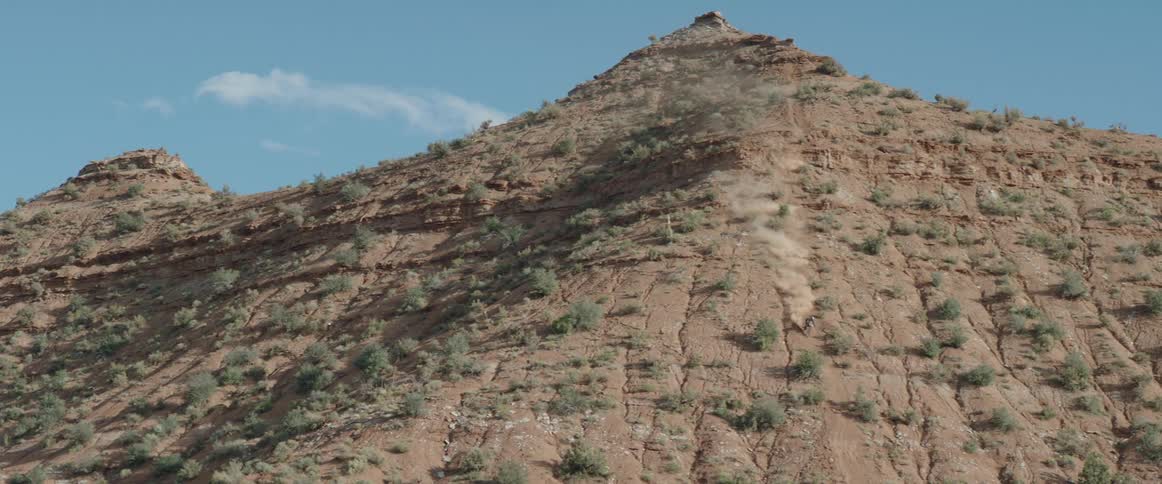 A person on a bike riding down a mountain in Utah with the sky and clouds in the background
