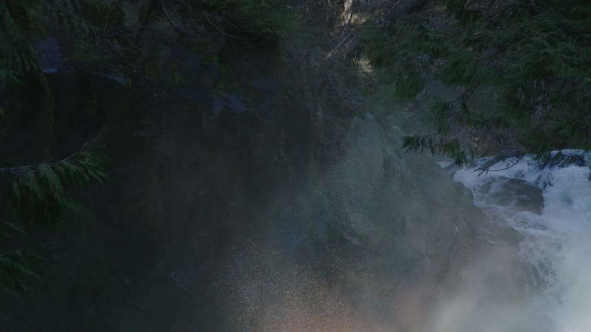 Mist explodes upward into the shadow of a large river canyon refracting light into a rainbow prism deep in this wilderness paradise