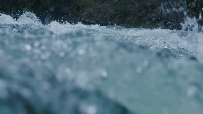 Water splashes violently in the rapids of a river during the day with a particularly dynamic foreground in this unique perspective
