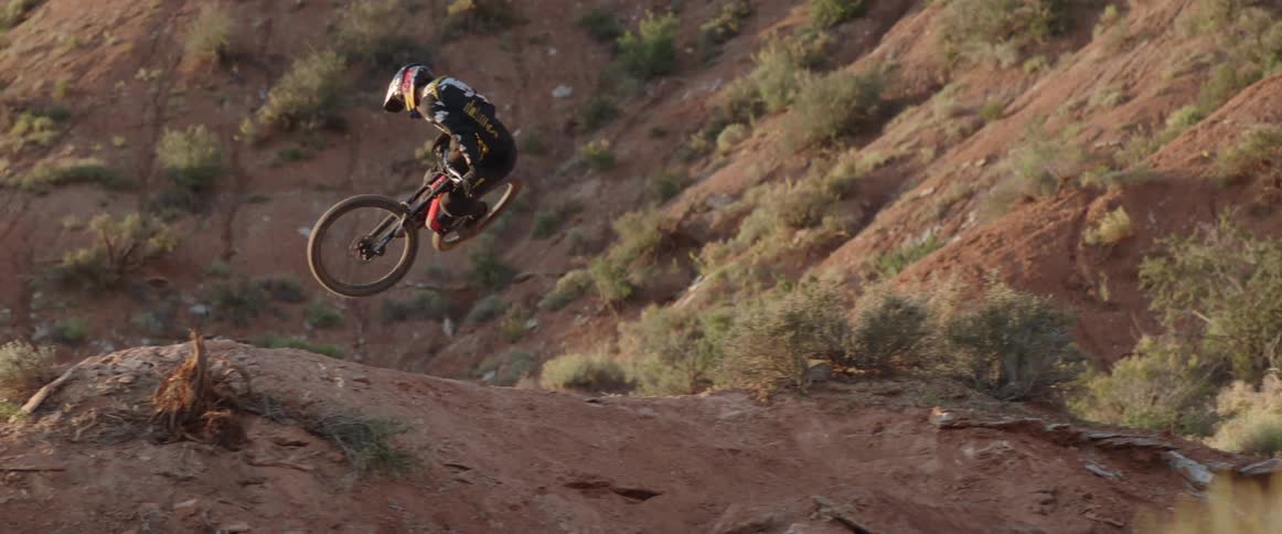 A cyclist whips their bike sideways over a jump in the desert