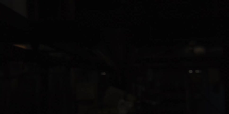 The bulbs of a fluorescent ceiling light blink in a dark room