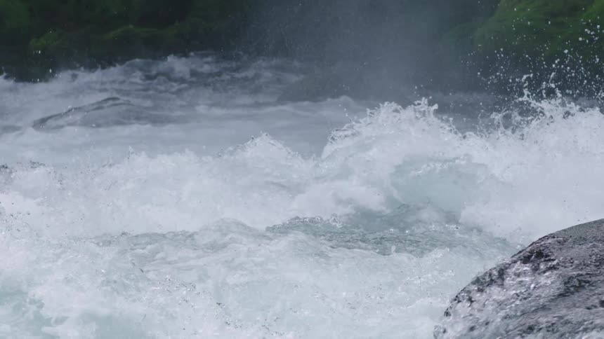 Static shot of water exploding over the lip of a waterfall in a pristine and untouched river environment