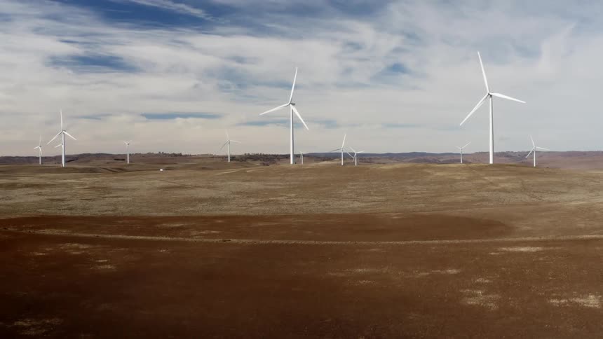 Wind turbines spin on a wind farm in vast grassland during the day